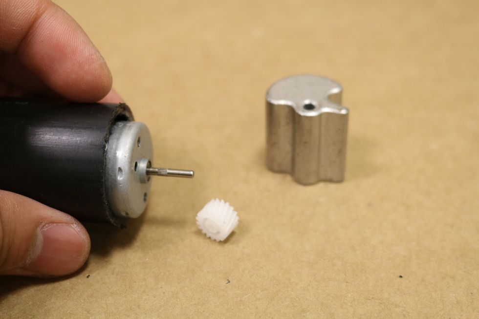 Take out the gear on the shaft of the motor. Put some hot glue in the hold of the eccentric weight, then attach the eccentric  weight to the motor.