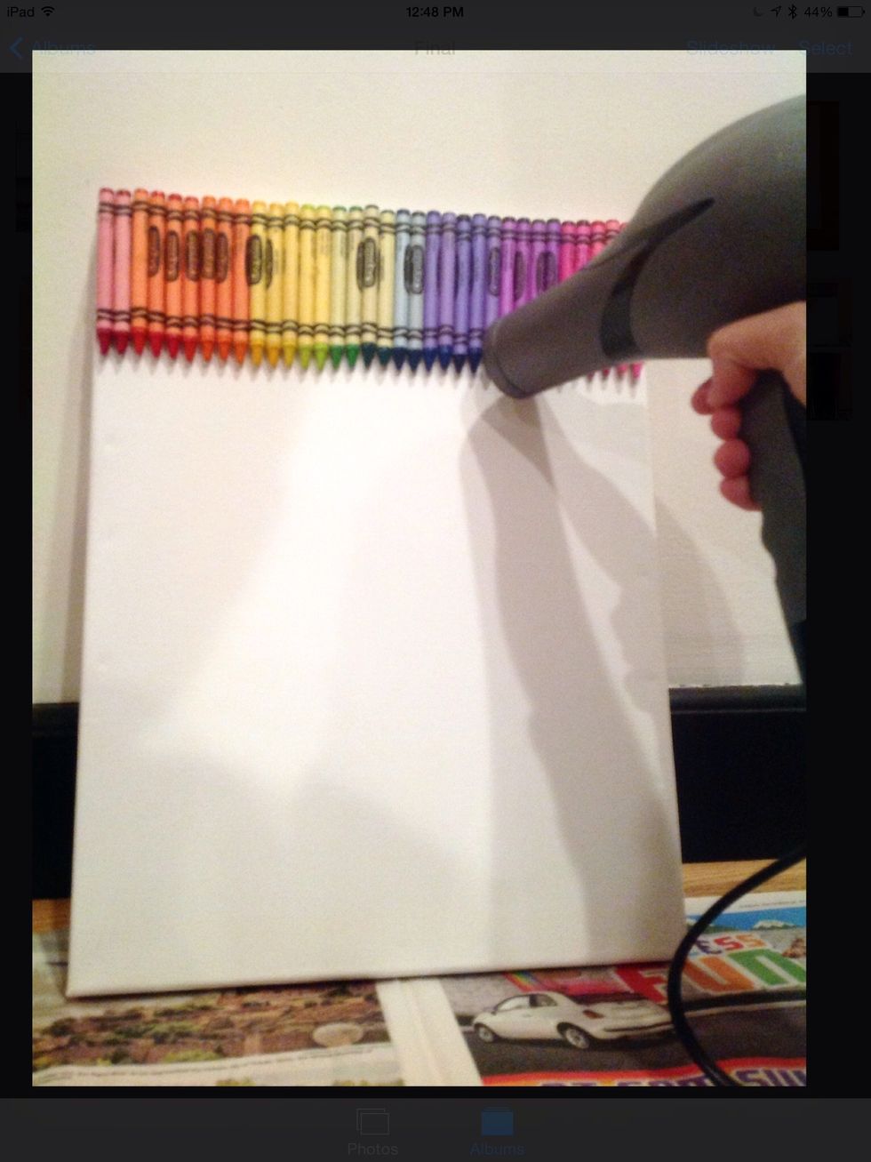 Take out your blow dryer and move it from top to bottom on the canvas so each crayon is evenly melted. The crayons will start to drip down onto the bottom of the canvas.