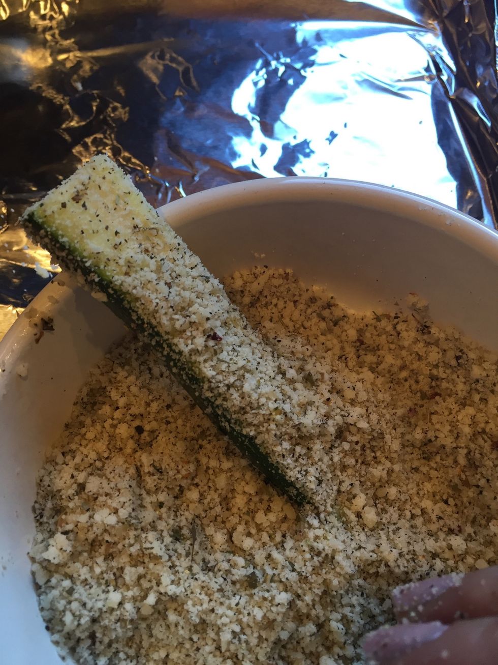 Take pieces of zucchini individually and sprinkle the cheese mixture on top. It should stick to the oil, more like a bread crumb coating.