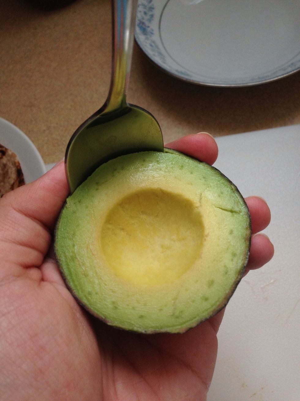 Take spoon and glide around whole avocado