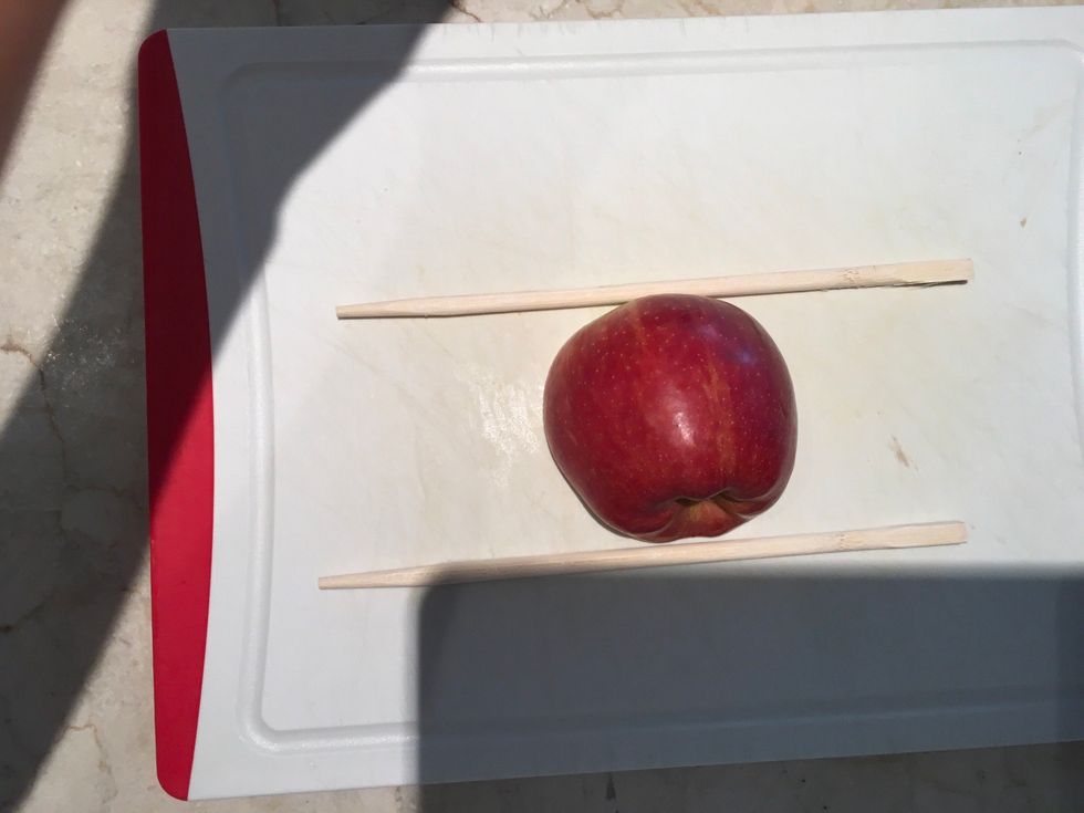 Take the bottom half of the apple and place it in between the chopsticks
