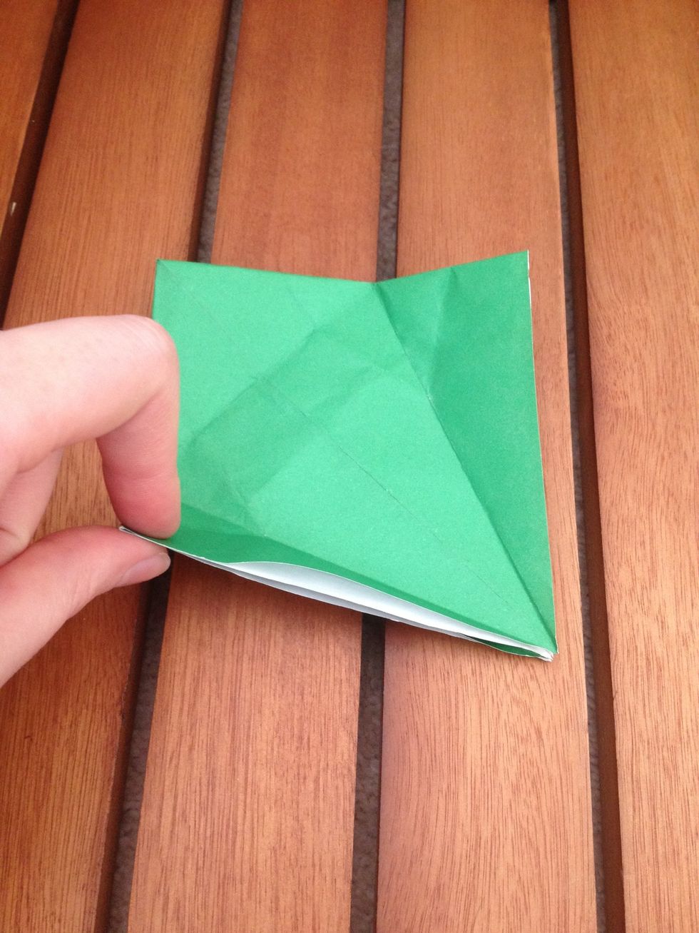 Take the bottom left corner and fold it so it lines up with the crease down the middle of the square.