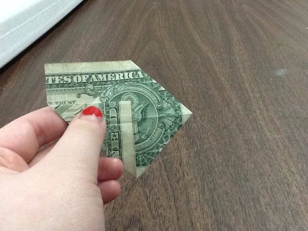 Take the bottom left corner of the dollar and fold it up to reach the center of the circle above the karate eagle. Make sure the line you create is straight. Use the angles above and below as a guide.