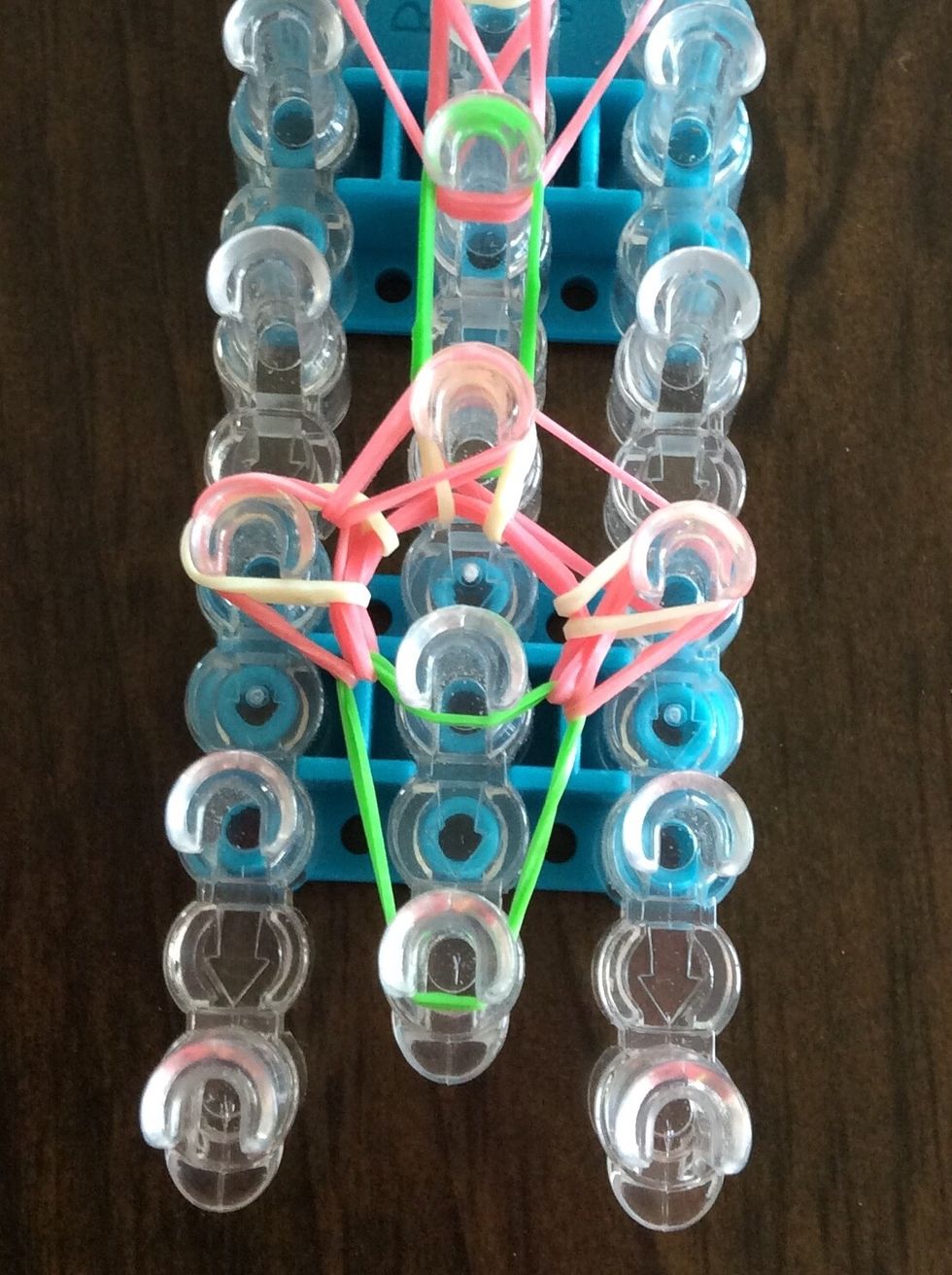 Take the bottom pink band on the third left peg and bring it to the third middle peg.