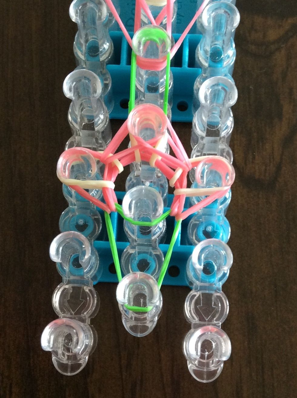 Take the bottom pink band on the third right peg and bring it to the third middle peg.