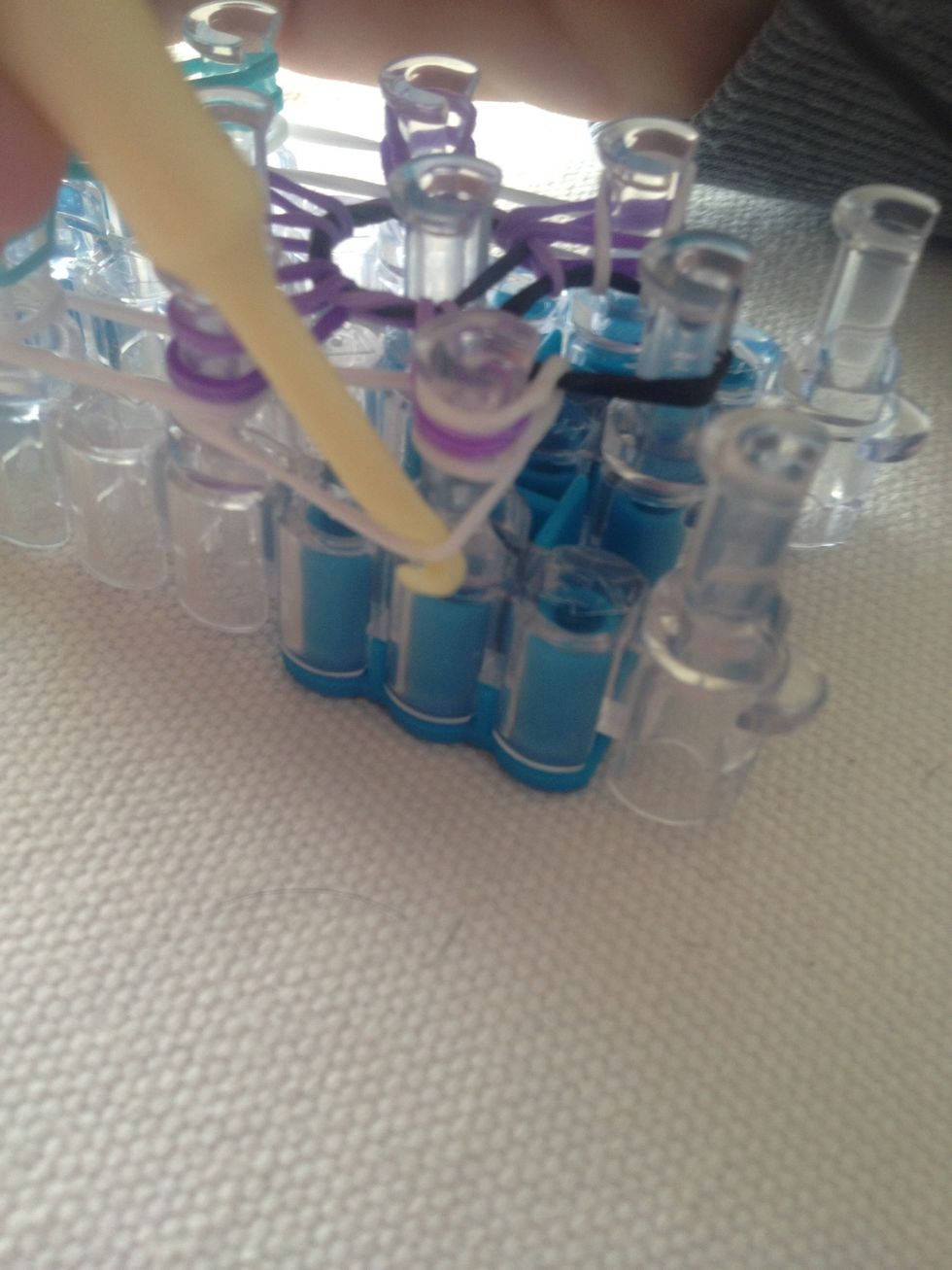 Take the bottom rubber band and pull it through the top and hook it on the next peg forward. Keep on going until you reach the top. (This is just showing you the bottom band).