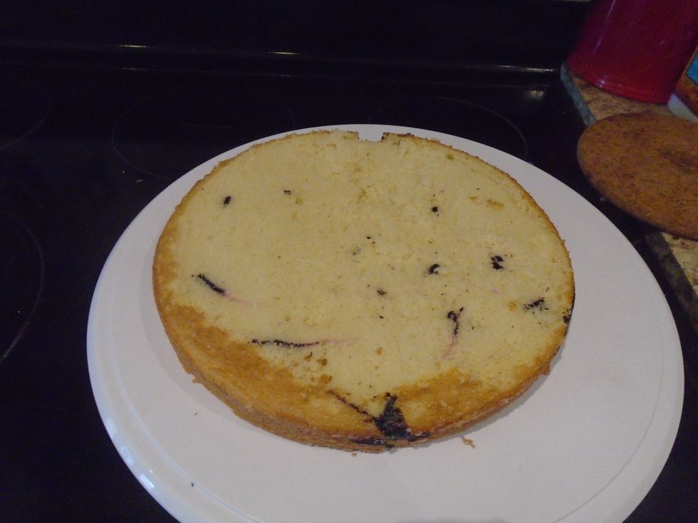 Take the cakes out of there pans and lay them on a cutting board big enough for the both of them. Cut off the tops of the cake to make them even, this is called leveling the cake.