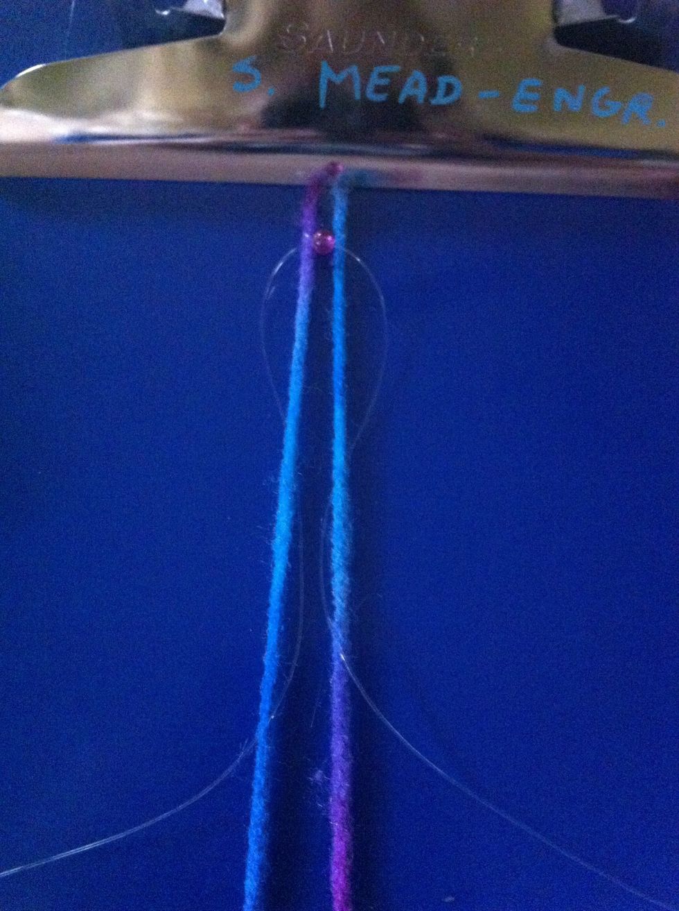 Take the clear string in the right side and stick it under the yarn strand on the right then pull though. Do the same on the left side.