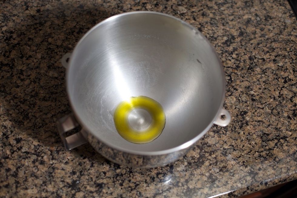 Take the dough out of the bowl and set aside.  I normally hold it in one hand while I add about 1-2 tbsp olive oil into the bowl.  Put the dough in the oil and swirl it around to coat.