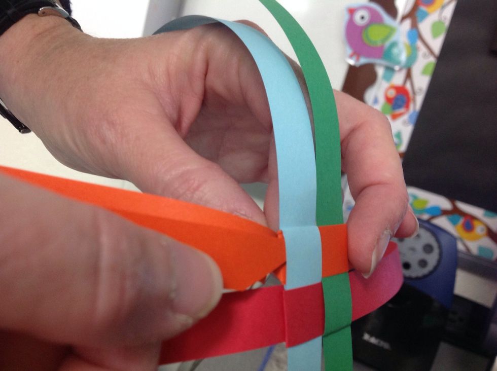 Take the end of the strip and place it through opening next to the base of the triangle you just created.