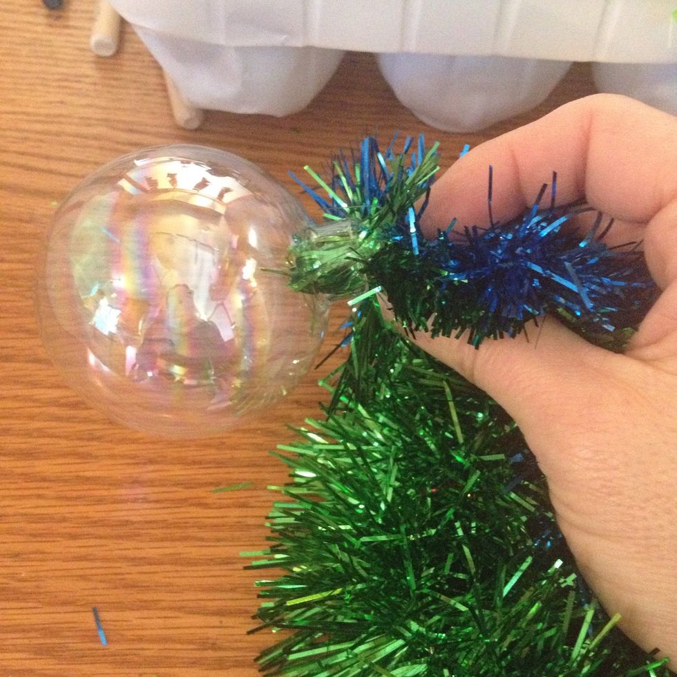 Take the ends of both strands and begin feeding them through the top of the ornament.
