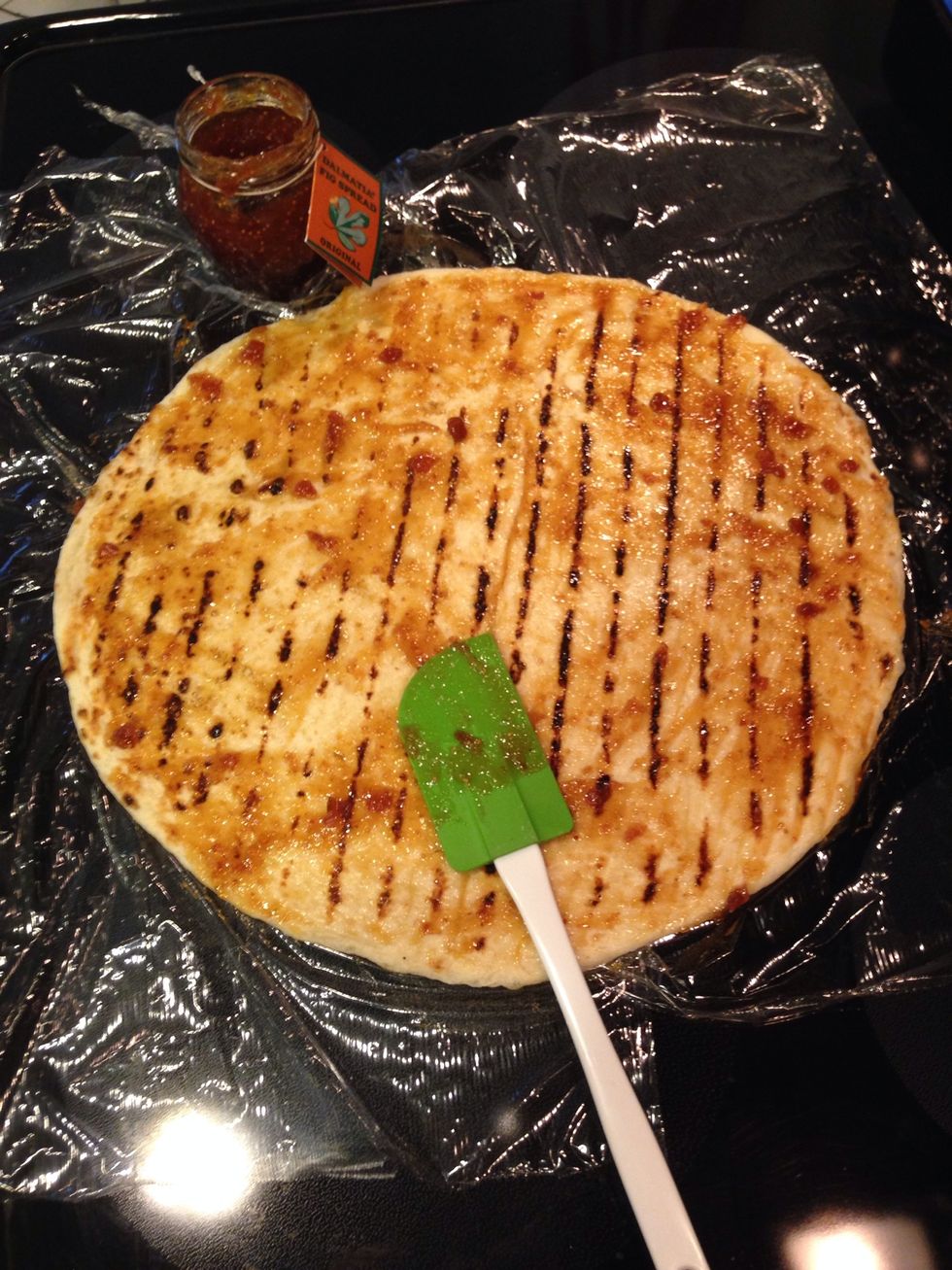 Take the fig spread and smear it all over the pizza. Get every part of it. But don't put too much because it will be to sweet. It will caramelize in the oven and become really nice.