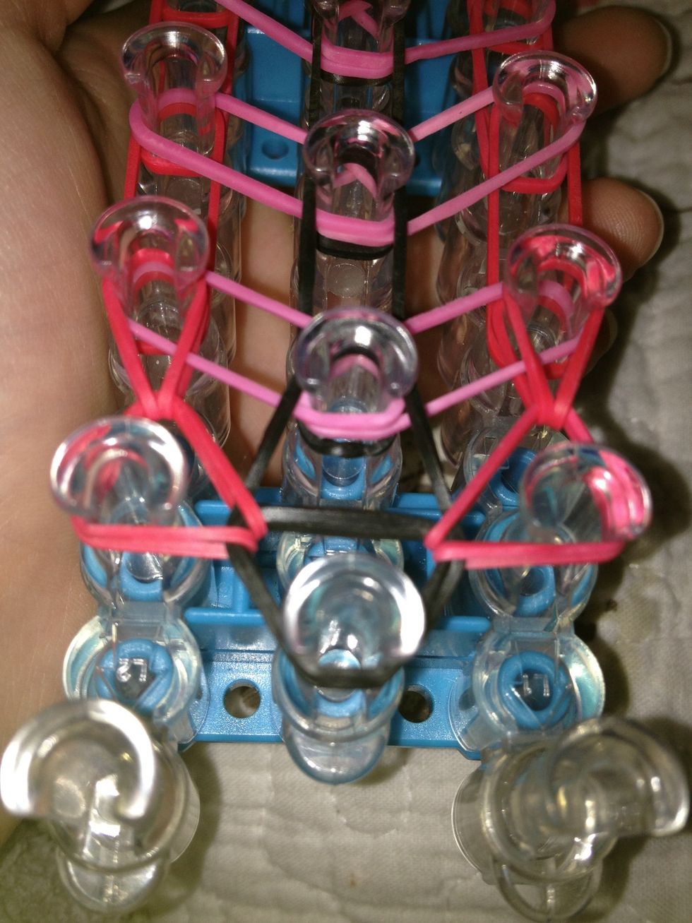 Take the first pink rubber band and bring it to the left and then take the last pink band and pull it to the right