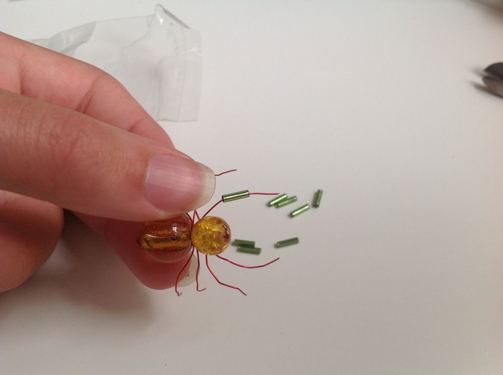 Take the green beads and put them on the wire.