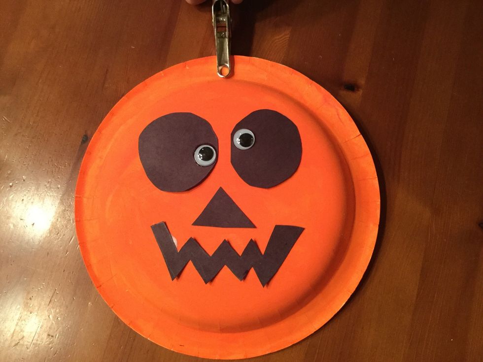 Take the hole puncher and punch a hole in the top center of the paper plate pumpkin.