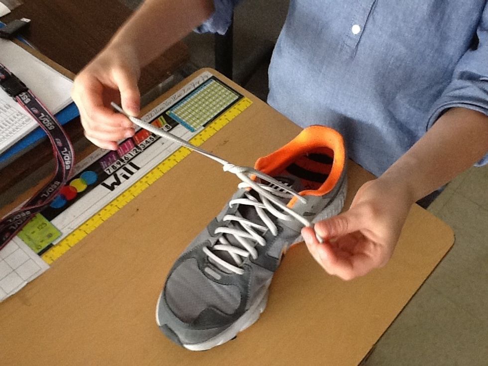 Take the left lace and pull it forward over the right lace.