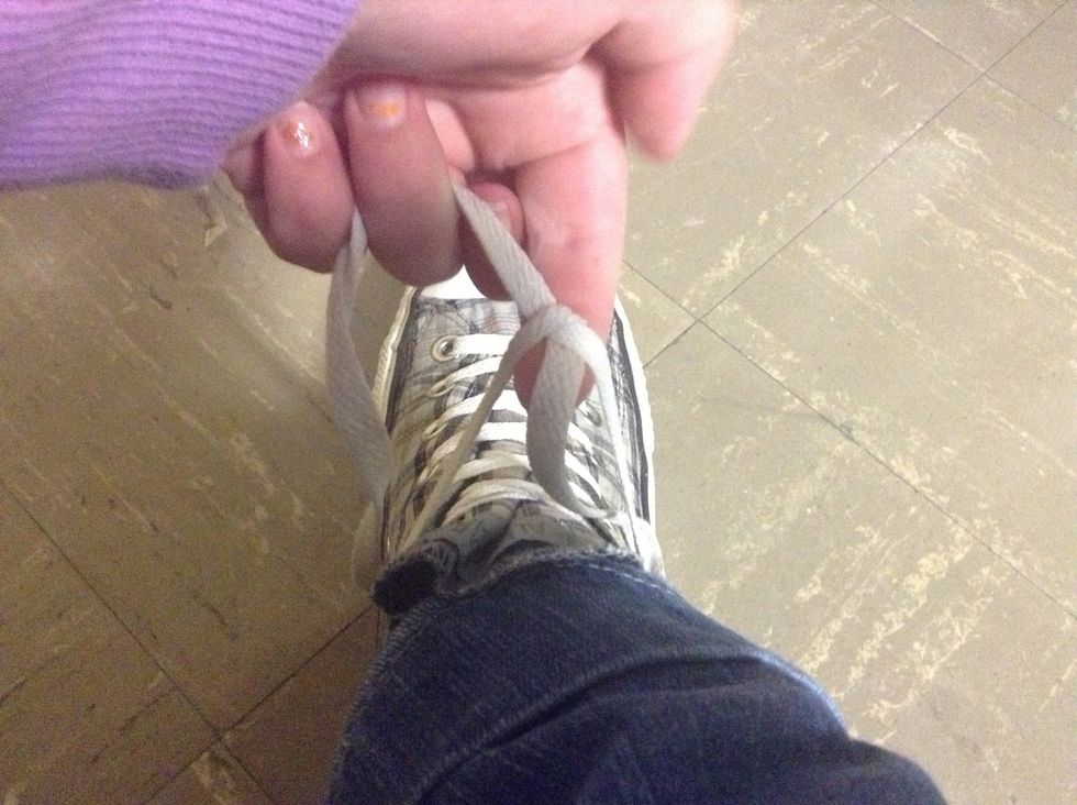 Take the left lace and pull it underneath both laces.