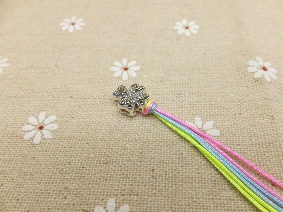Take the left peach cord over the holding cords and put it under the right peach cord.