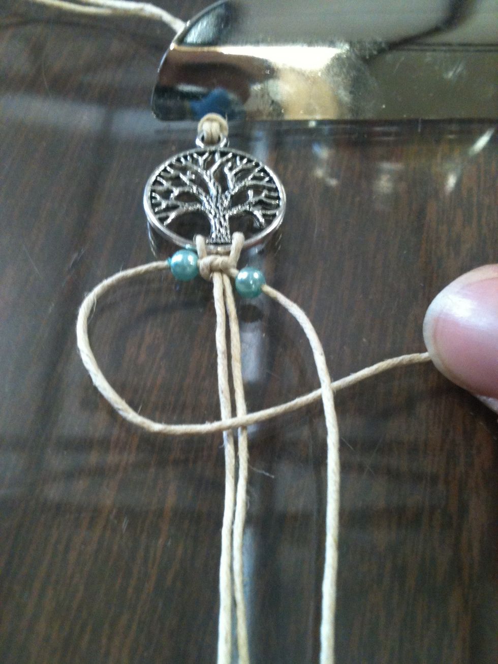 Take the left string and place it on top of the string that is attached to the pendant. Now take the right string and place it on top of the left string. Tuck the right string under the... NEXT PAGE\ud83d\udc49