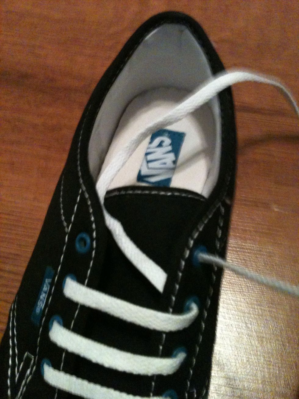 Take the left string (which is now on the right) and pull it through the bottom of the last right eye