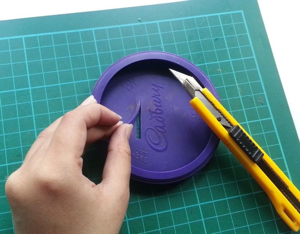 Take the lid and cut out a thin strip out of the lid. The thin strip should be enough to slide in a coin through it.