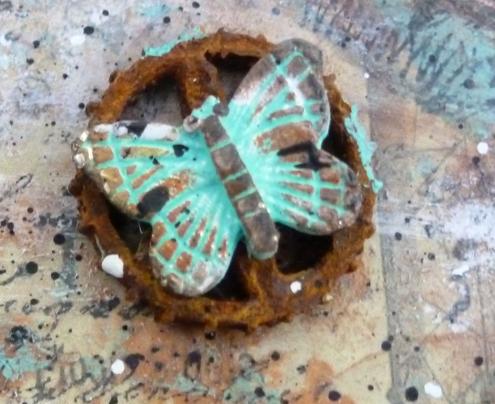 Take the loop off of butterfly charms with pliers. Paint with patina paint. Let dry. Use Prima Chalk edgers in rusty keys and dark rust to highlight the detail. (Splatters come in last step).