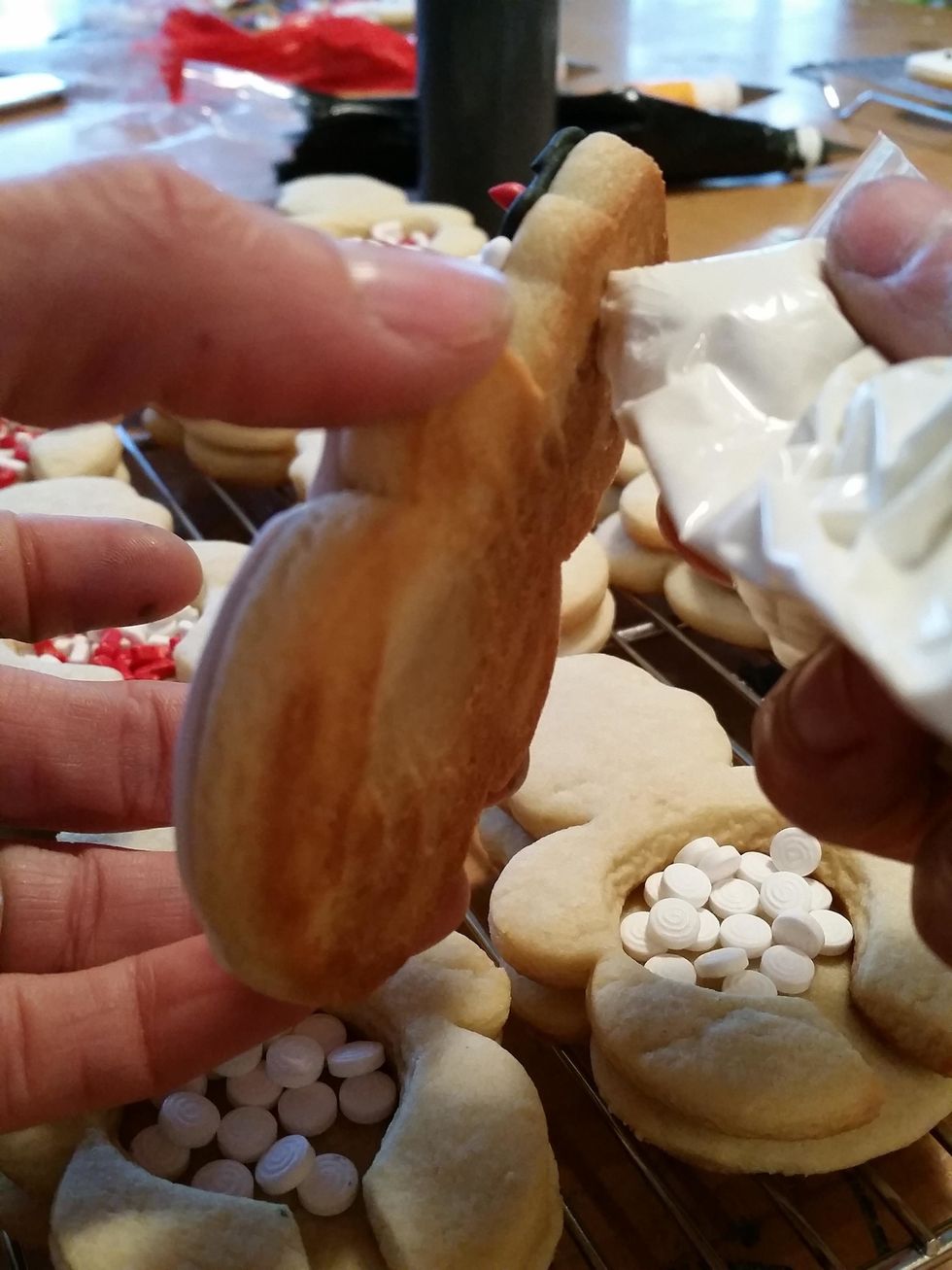 Take the melted candy white chocolate melts and trace the back of the decorated, dried cookie. Sandwich down on the already "glued" sprinkle filled portion