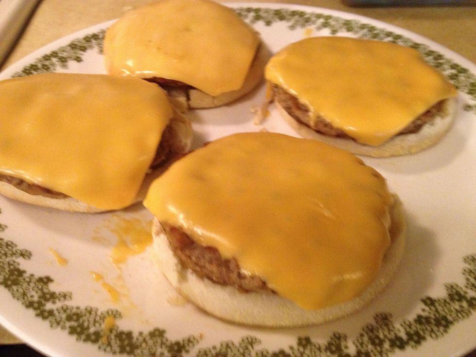 Take the muffins out of the toaster. Remove the patties w/cheese from the skillet and place them on the bottom half of the muffin as pictured.