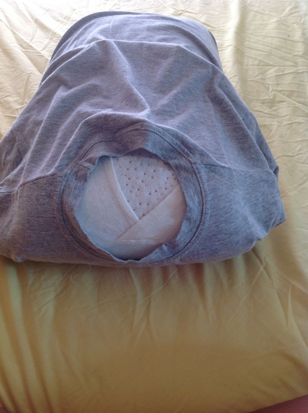 Take the neck of the t-shirt and fold it on the back of the pillow