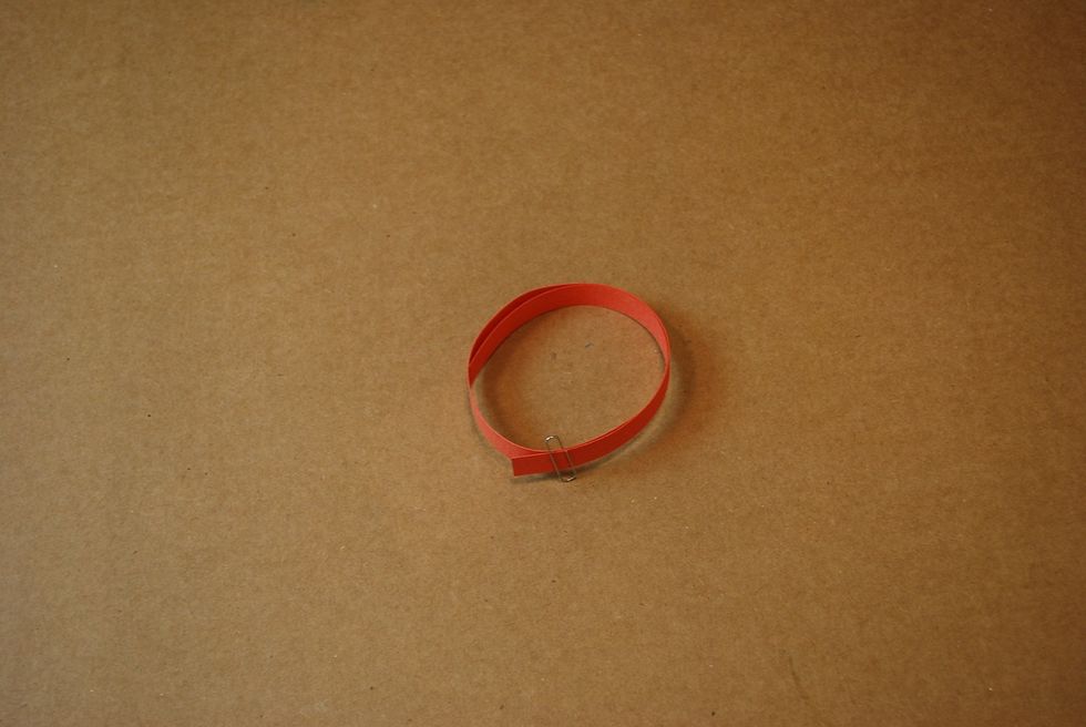 Take the orange strip and coil it to the size of your whole star and keep it in place with a paper clip.