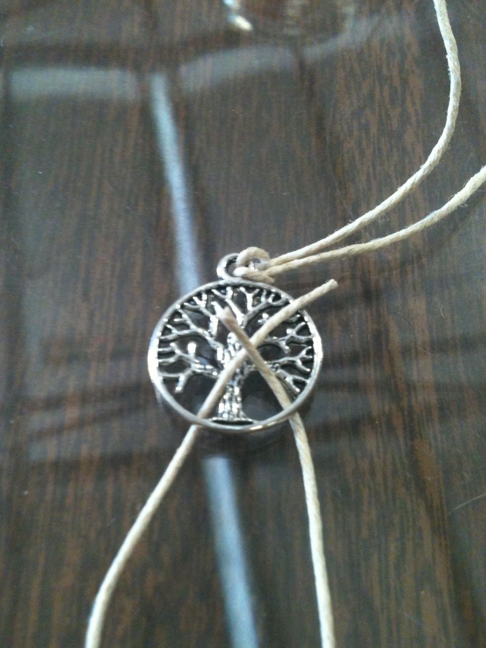 Take the other string that you cut and stick it through the pendant like this.