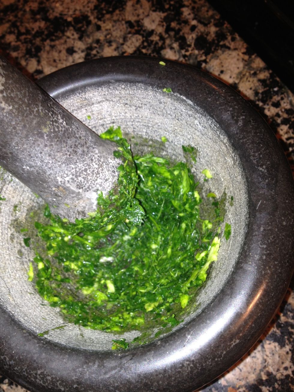 Take the parsley leaves and bash them with the garlic clove and a couple of pinches of salt in a pestle and mortar, until you get a fine paste.