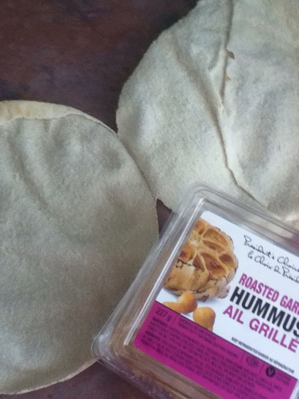 Take the pita bread, open it, and take roasted garlic hummus ( or other hummus )