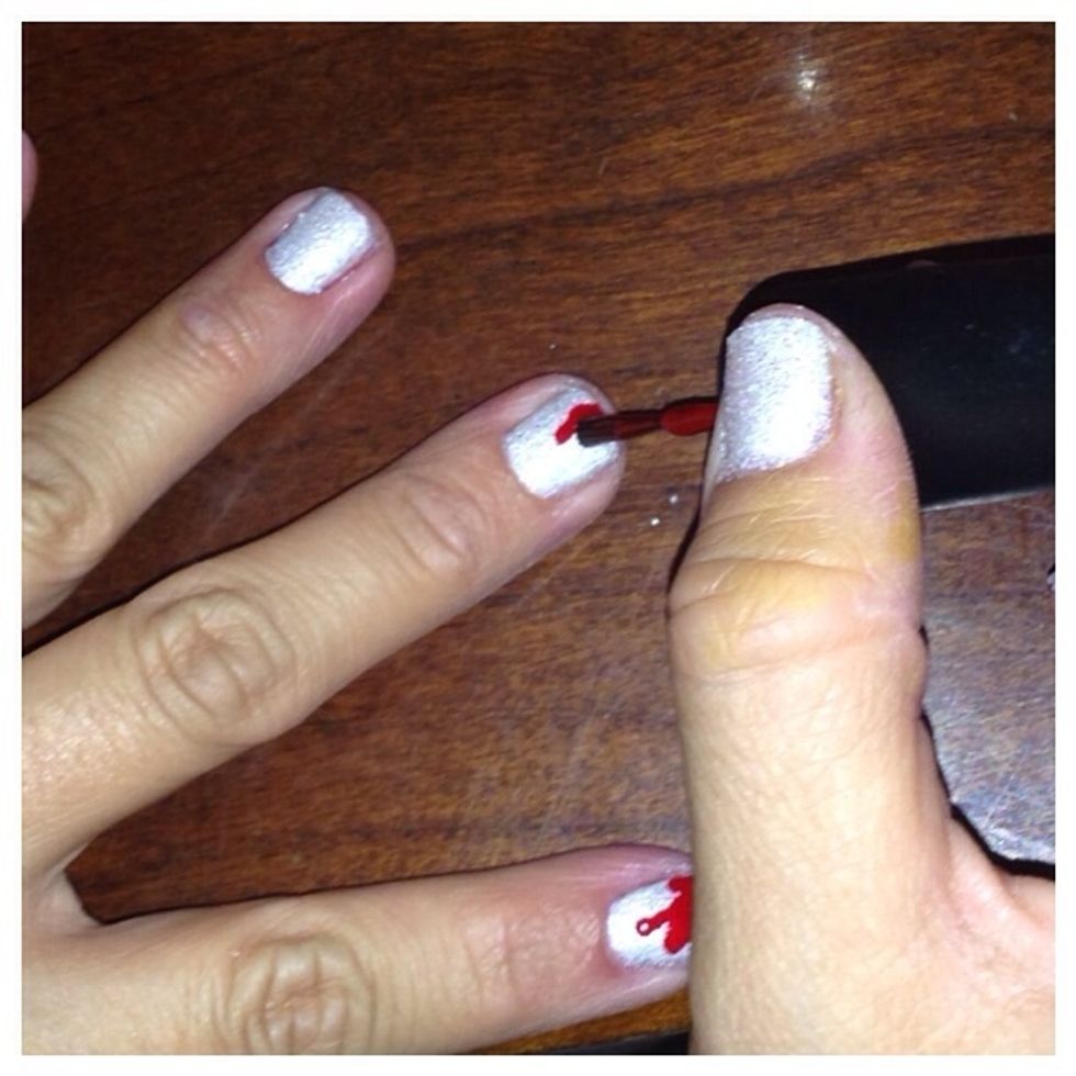 Take the red polish and allow enough polish to stay on the brush so that it will drip onto tip of nail. You will be able to make a patter of blood splatter