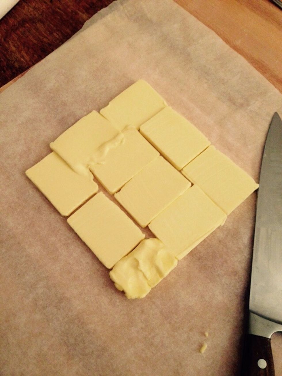 Take the remaining butter and cut it in 1cm slices and arrange it in a square over a sheet of wax paper.