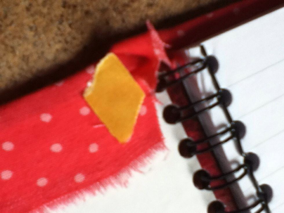 Take the remaining fabric, and move it to one side of the notebook. Stick it down with tape.