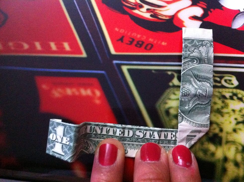 Take the right side and fold up between the letters "E" and the "S.". NOTE: This determines the width of the circle part of the ring.