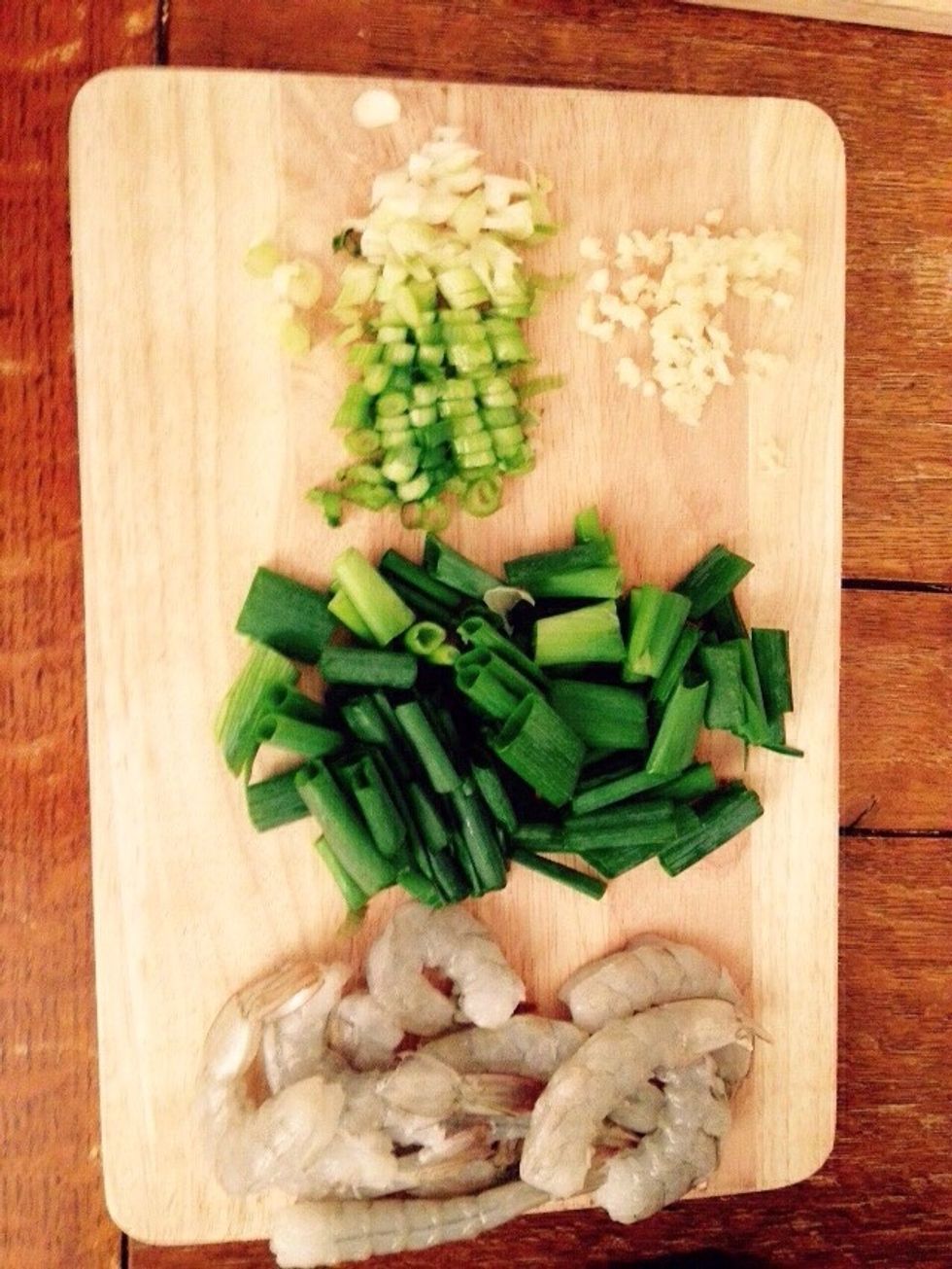 Take the scallions and chop the white bottoms finely, while leaving longer pieces on the top greener parts. Crush the garlic cloves.