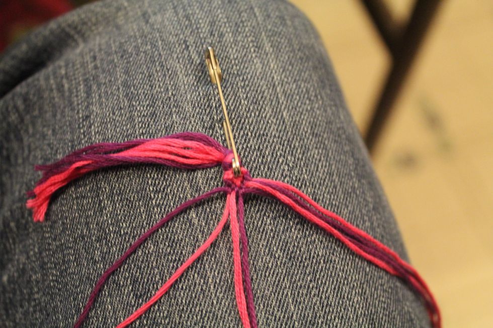 Take the second string in on the left side and tie a backward knot around the outside string on the left, going left.