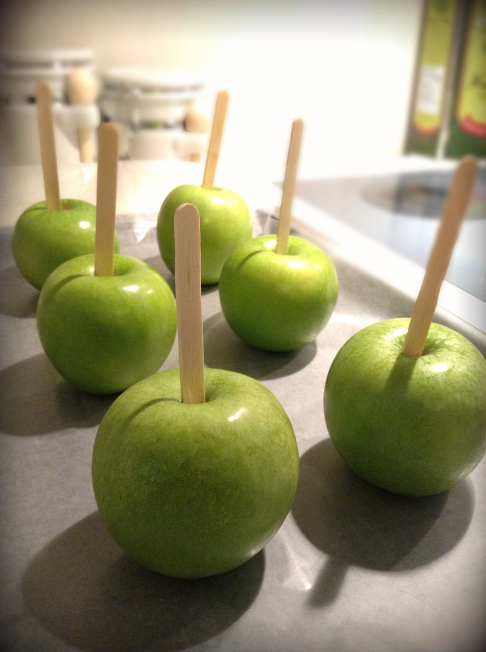Take the stems out of the apples by simply twisting them and then insert popsicle sticks.