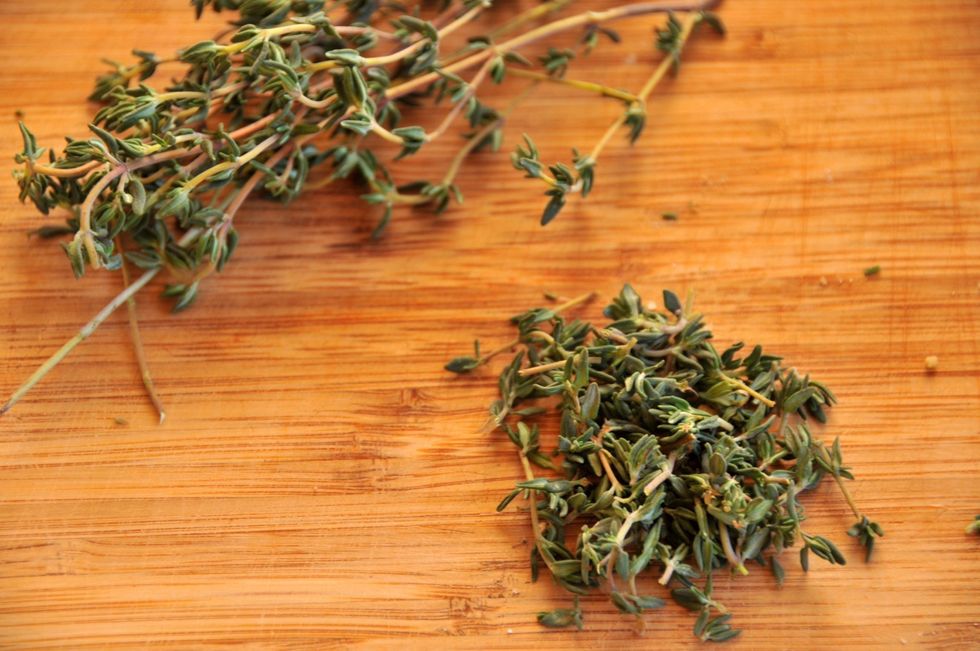 Take the thyme and grab it at the tip of the stem, pull your finger down the stem to remove the leaves. They come off easier if you go from top to bottom, against the direction they grow. Then chop.