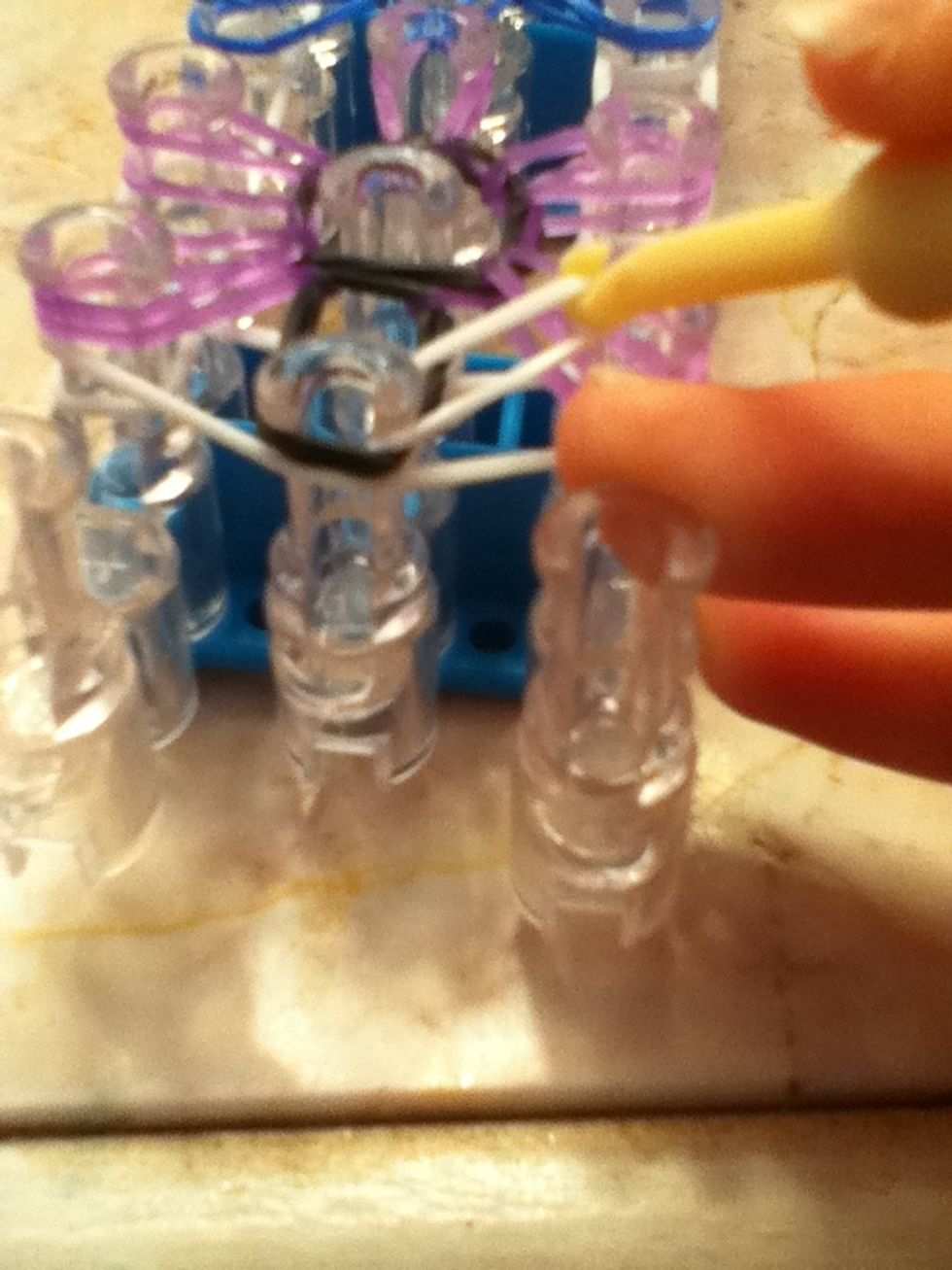 Take the white bottom rubber band and pull it over to the peg that is diagonal.