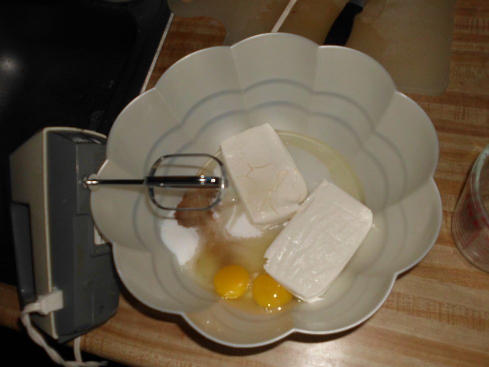 Take your cream cheese, and let it sit out to soften. Then place it in a large bowl, and add the sugar, vanilla extract, and then the eggs. Then stir with an electric mixer until well blended.