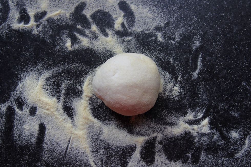 Take your dough out of the bowl, roll into a sausage shape and cut into five equal pieces. Any dough balls you don't use can be frozen. Roll out your dough to the same size as your pan base.