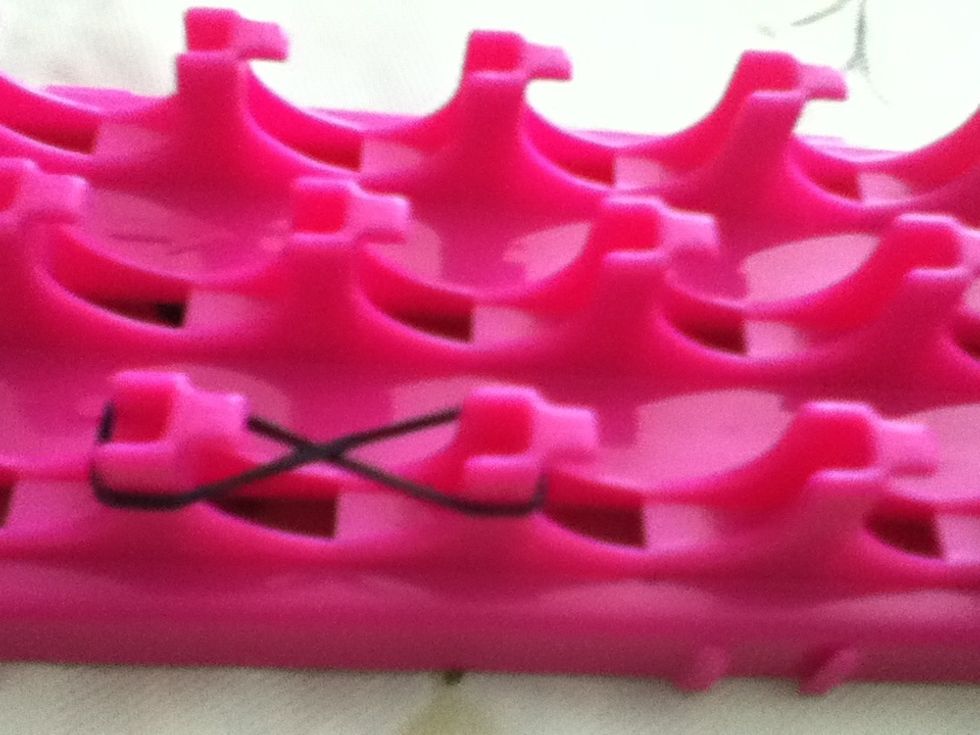 Take your first color and twist it like a figure 8, as seen above, and place it on two pegs.