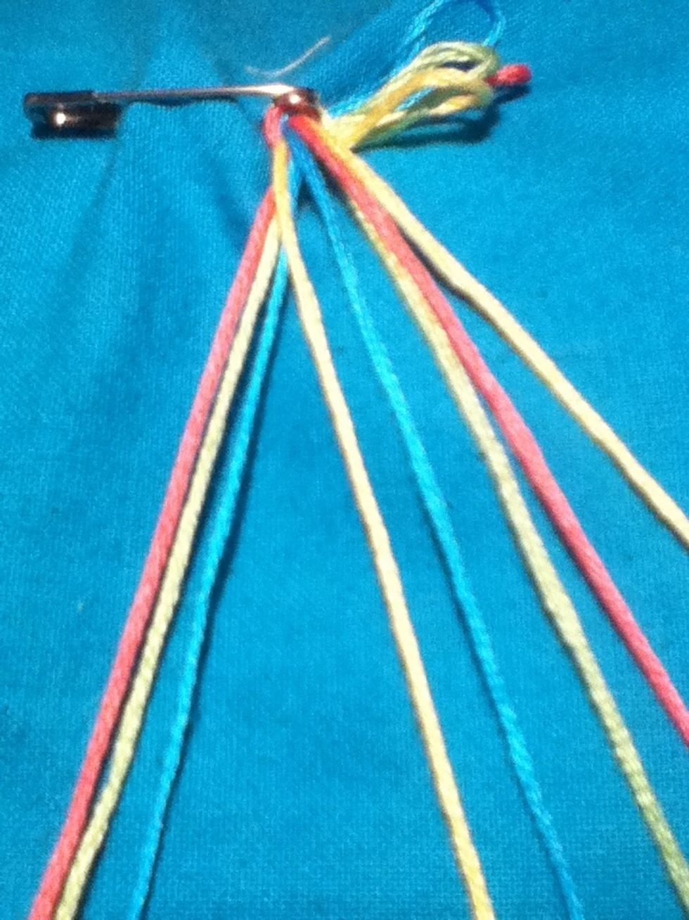 Take your first color on any side and bring it over the other colors and put it behind your last color on the other side
