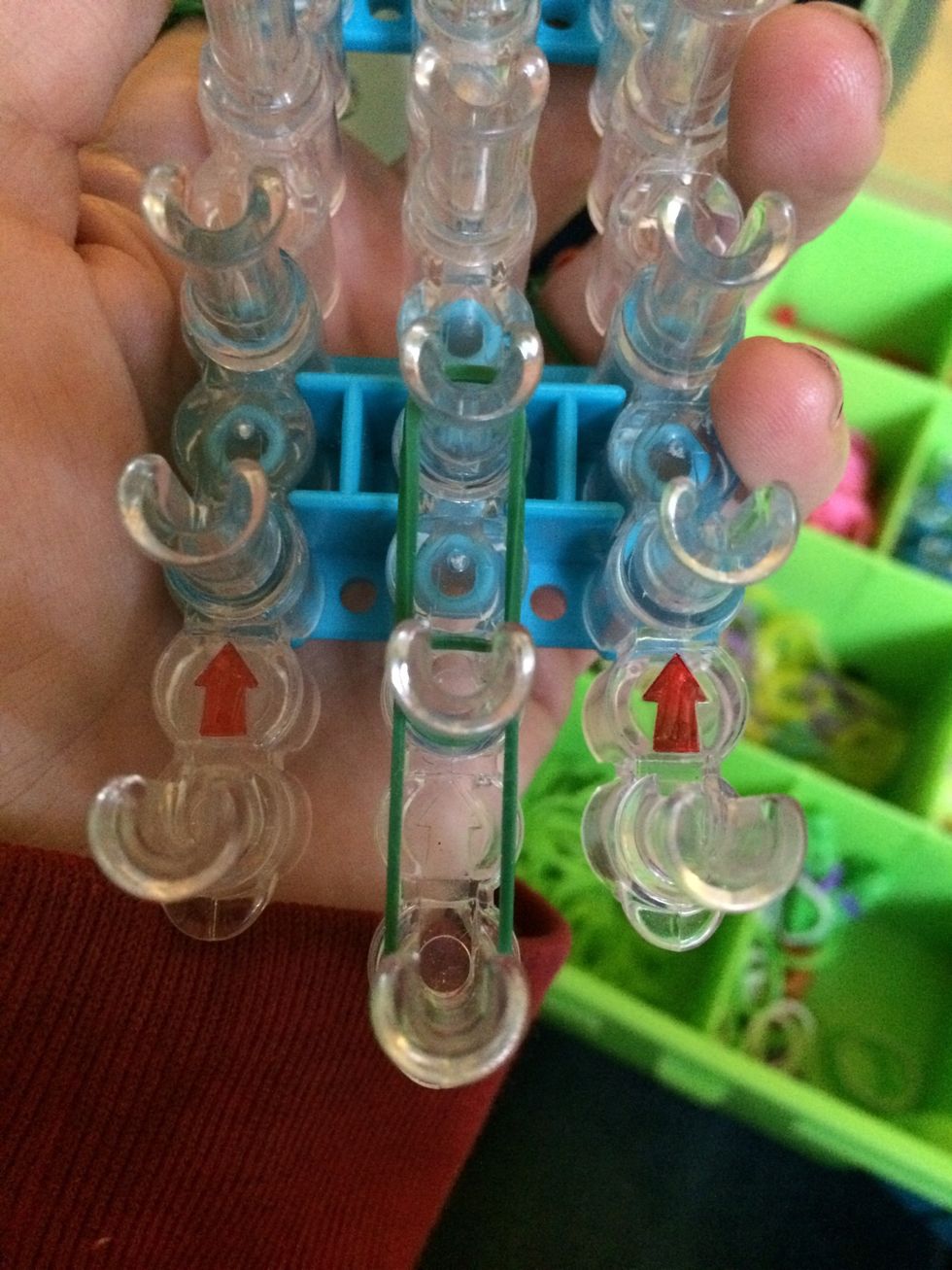 Take your first two bands and place them on the first two sets of pegs on the center like this. Start at the bottom.