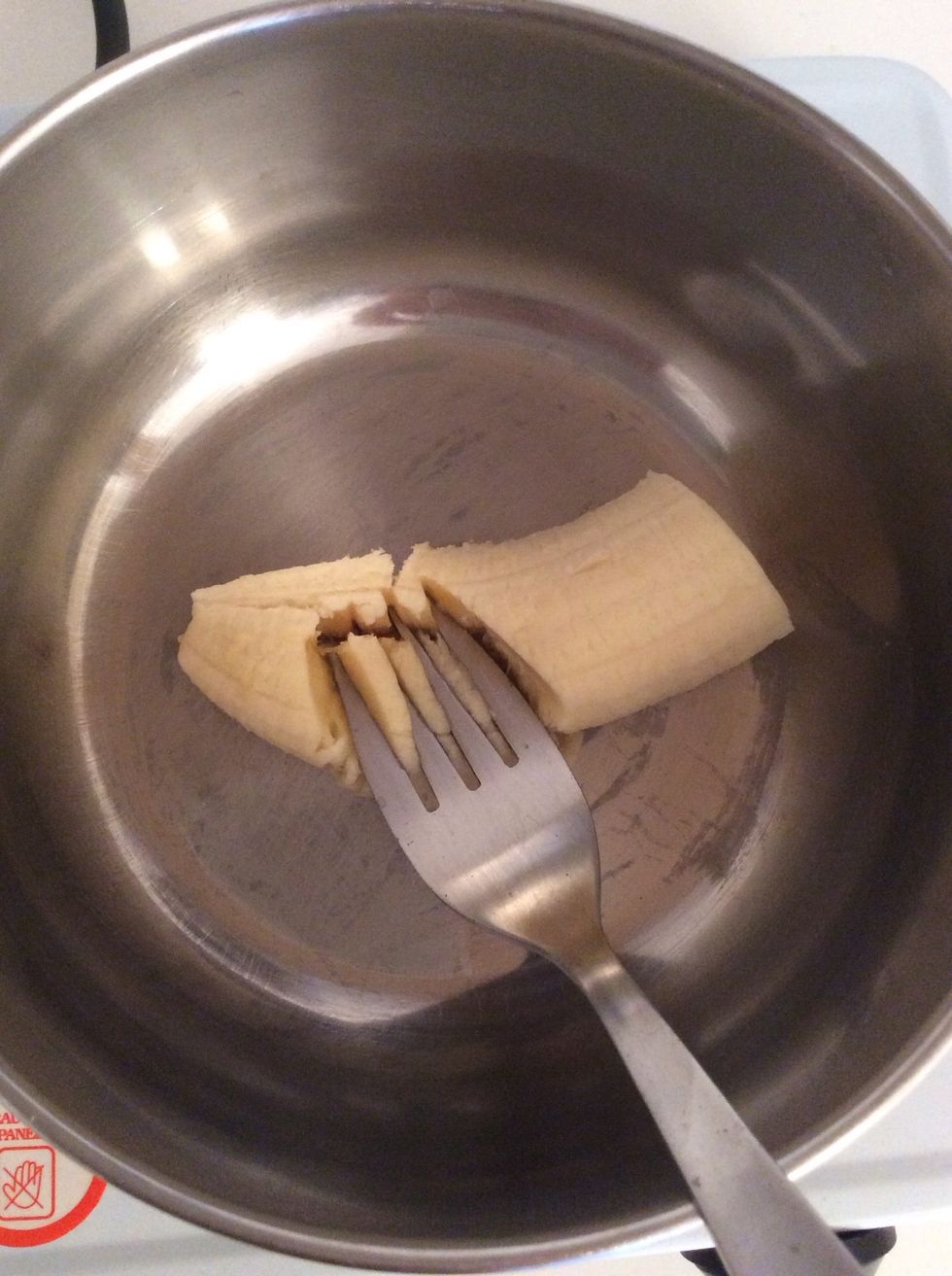 Take your fork and start mashing the banana.
