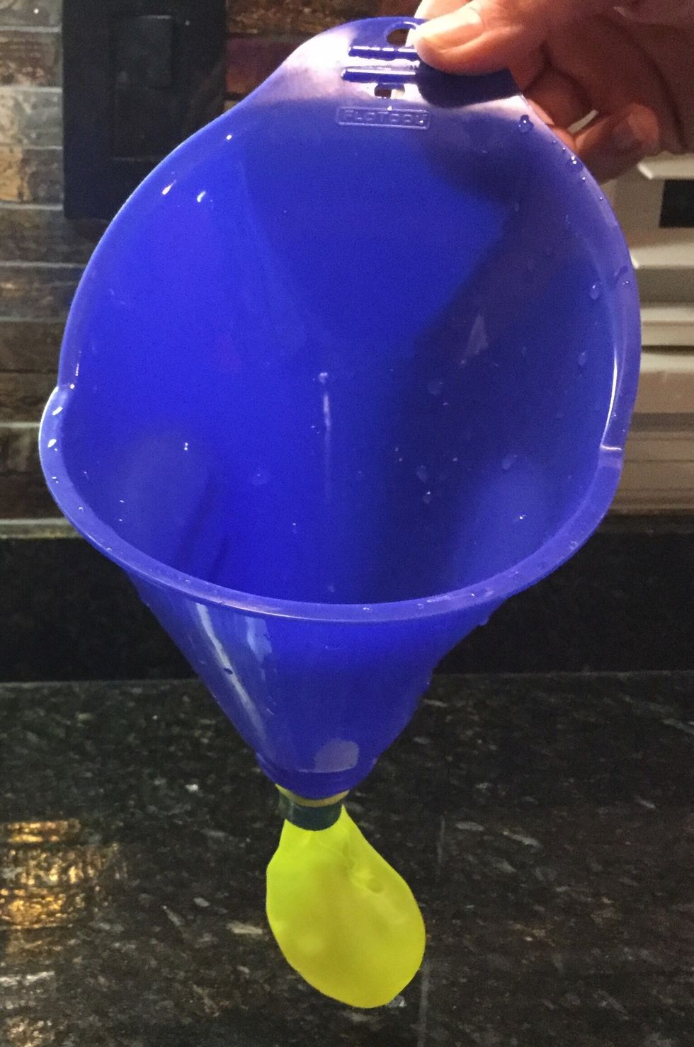 Take your funnel and place it inside the balloon.
