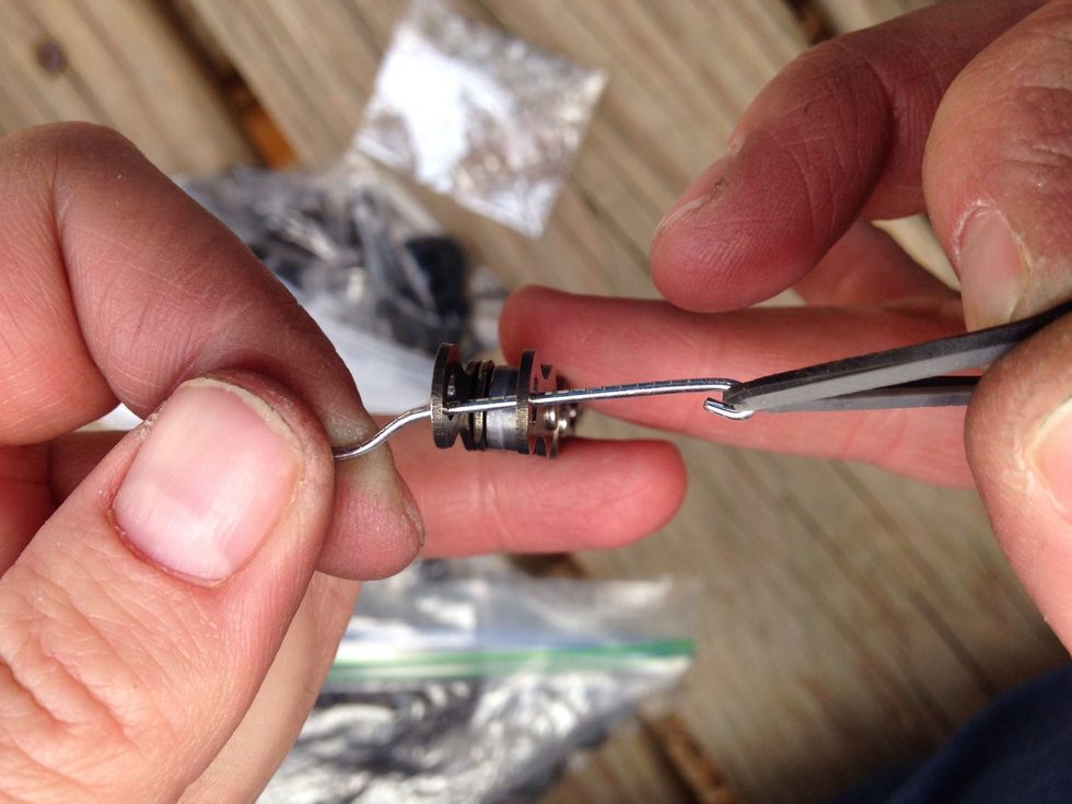 Take your paper clip and make it into a hook to help pull the rubber bands through the holes where the pin use to be